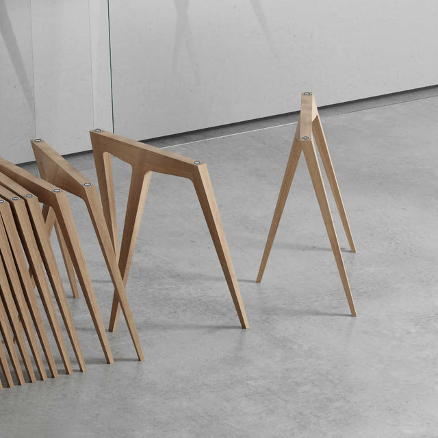 A series of Flex trestle table legs nesting neatly in a line. Its simple design allows for dense packing in a small space.